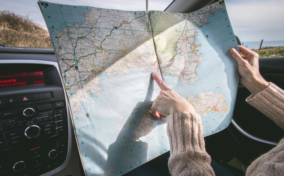 Free Image of Person examining a road map inside a modern vehicle. 
