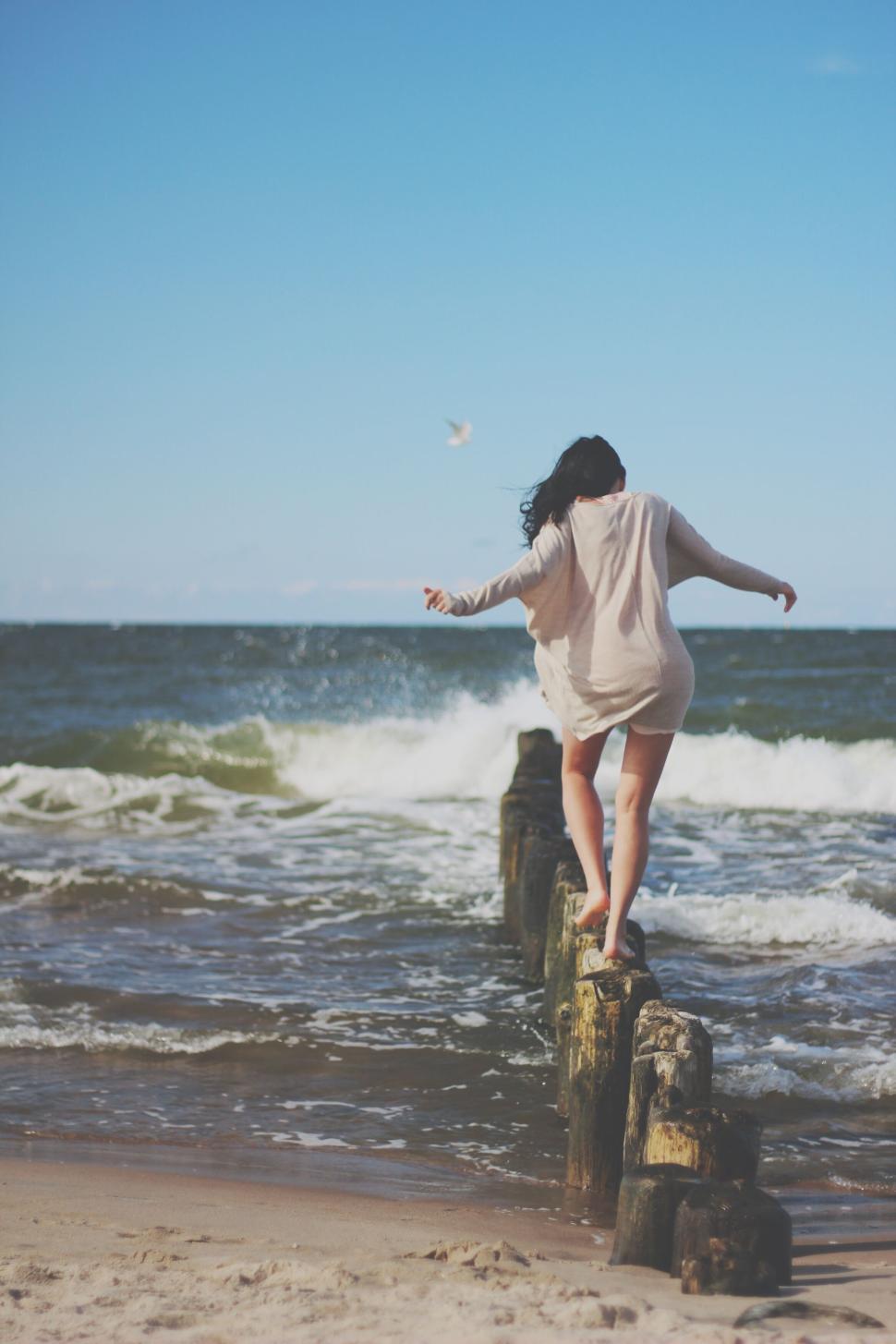 Free Image of Person balancing on a seaside wooden groyne in motion. 