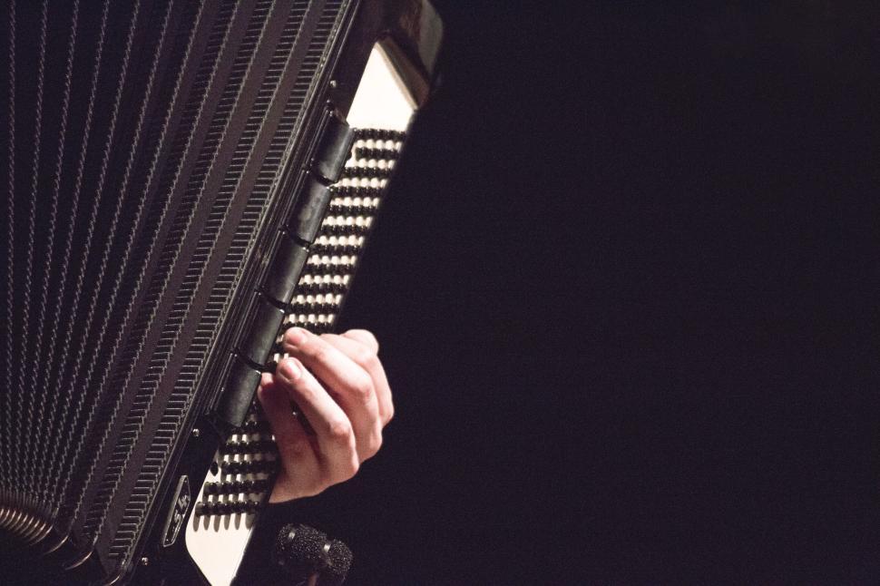 Free Image of Close-up of hands playing accordion in dark setting. 