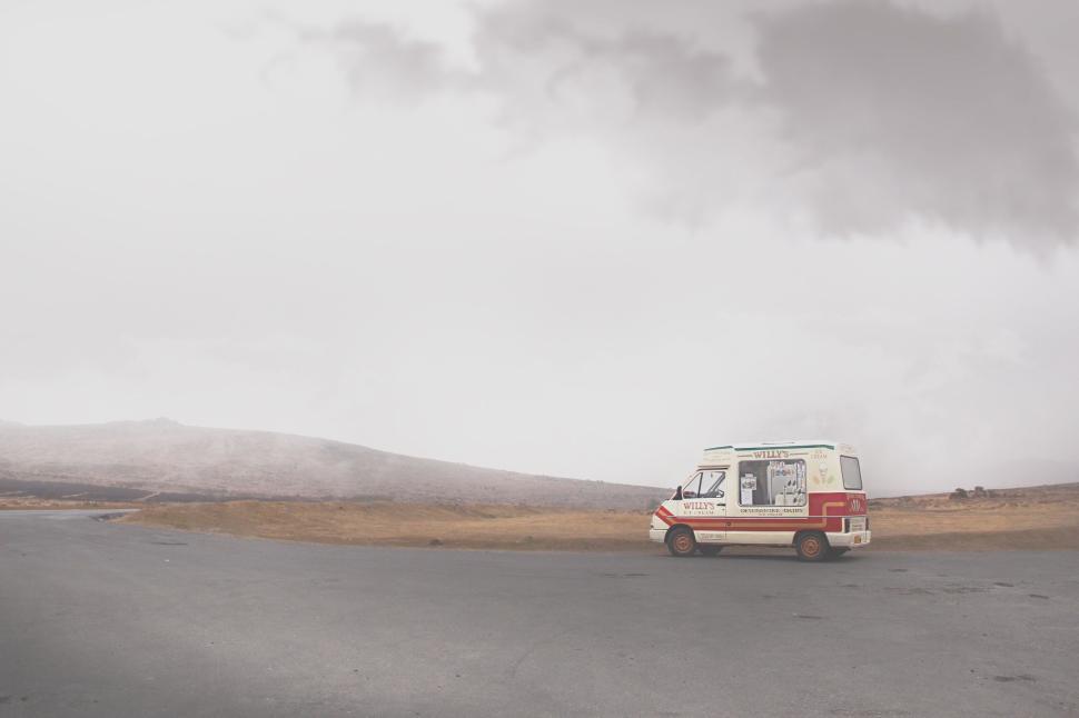 Free Image of An ice cream van parked on an empty road in fog. 
