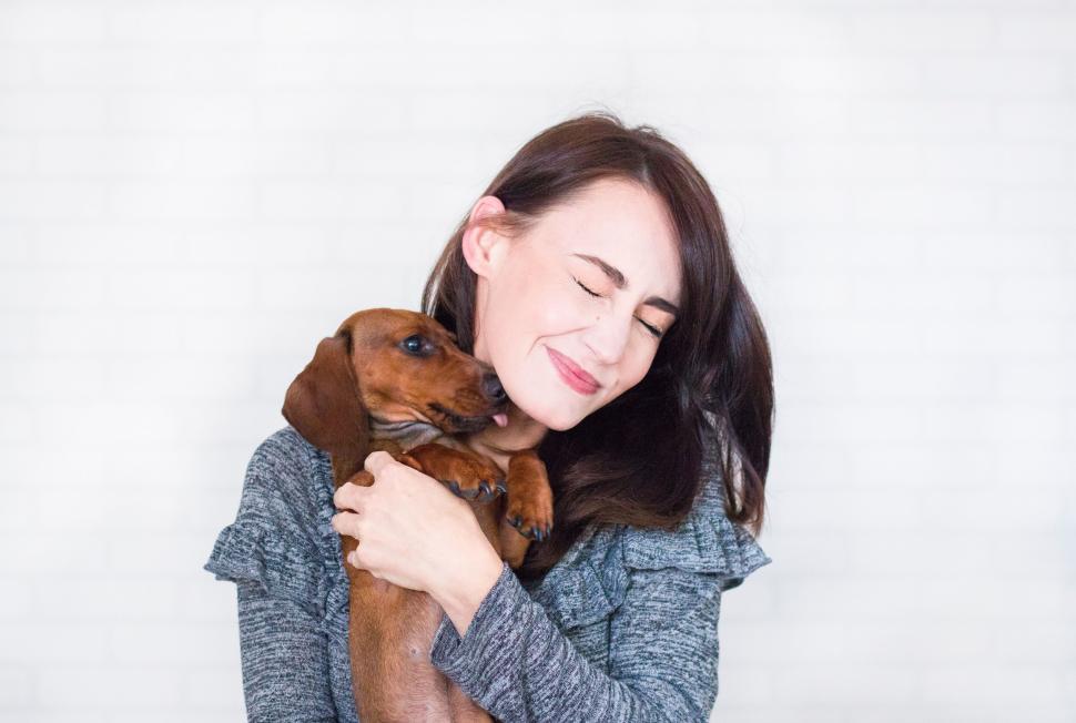 Free Image of Woman cuddling small dog with closed eyes and smile 