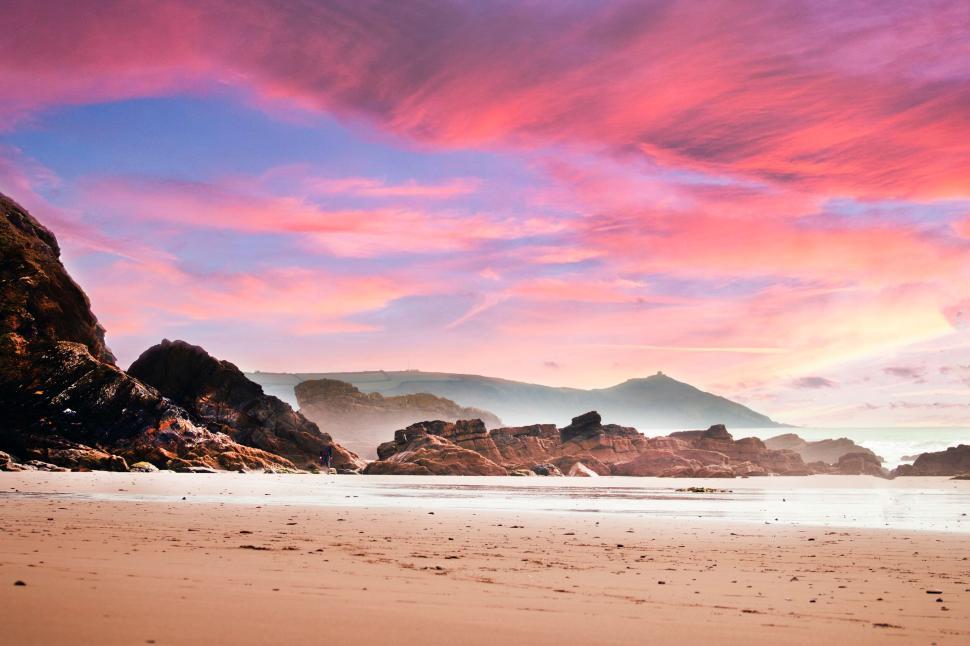 Free Image of Sunset view on a rocky beach with gorgeous pastel sky 