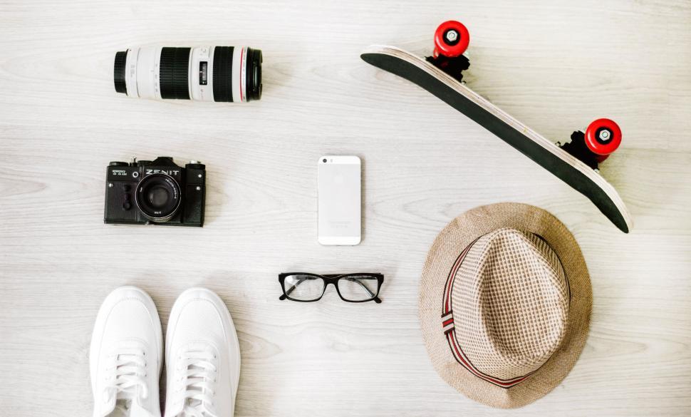 Free Image of Flat lay with skateboard, hat, camera, and other items. 