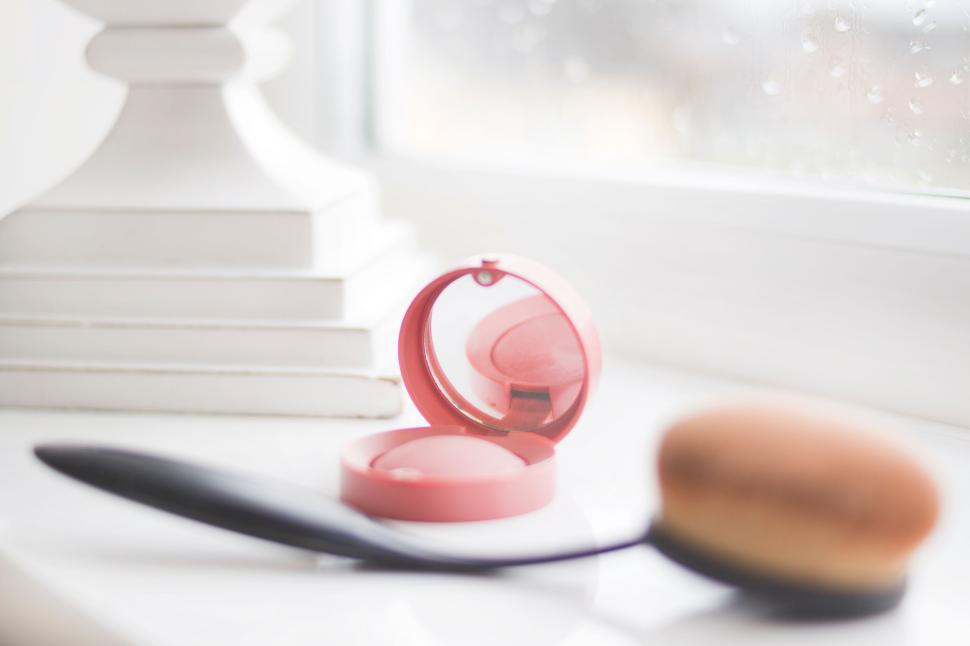 Free Image of Compact mirror case with makeup brush on table 