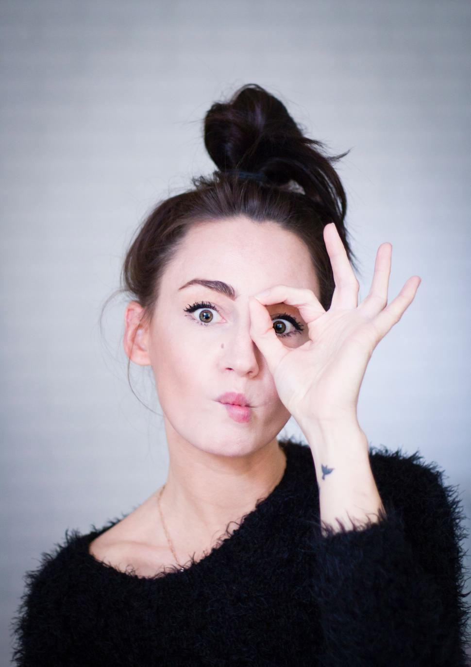 Free Image of Playful woman making an  OK  gesture with her hand 