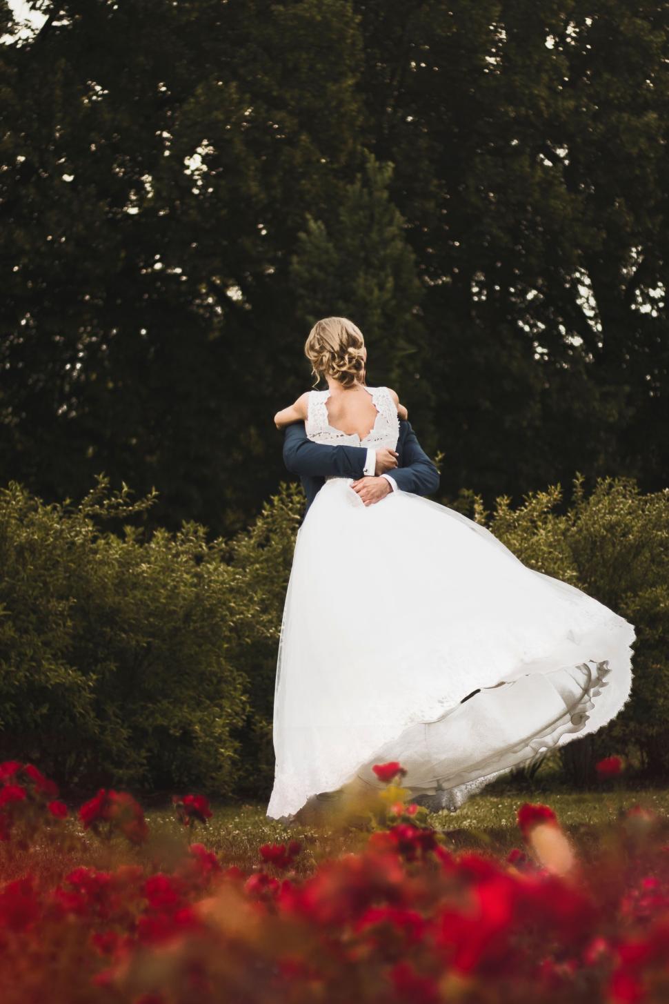 Free Image of Bride and groom embrace in a picturesque outdoor setting. 