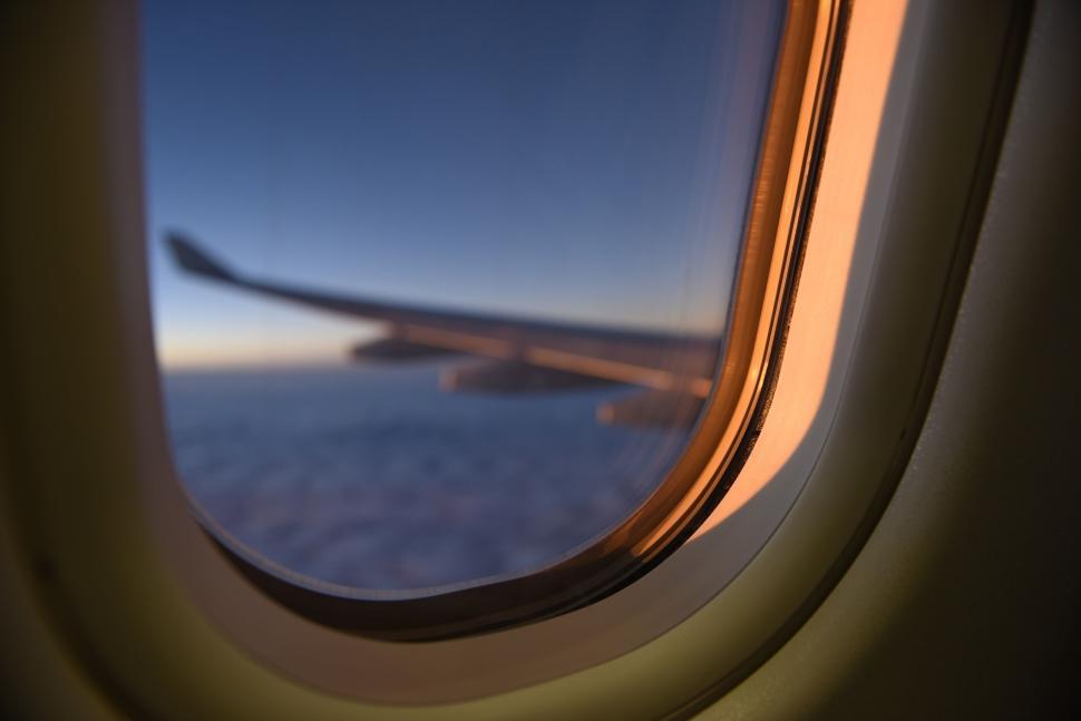 Free Image of Sunset view from an airplane window showing the wing. 