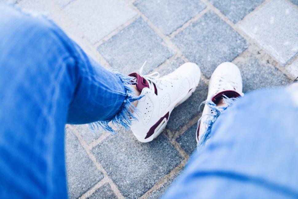 Free Image of Feet in white sneakers with maroon accents on pavement 