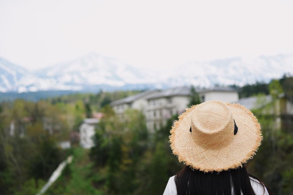 Free Image of Person with straw hat surrounded by scenic mountain view 