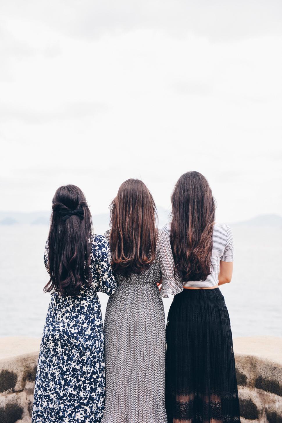 Free Image of Three women facing ocean with different outfits and styles 