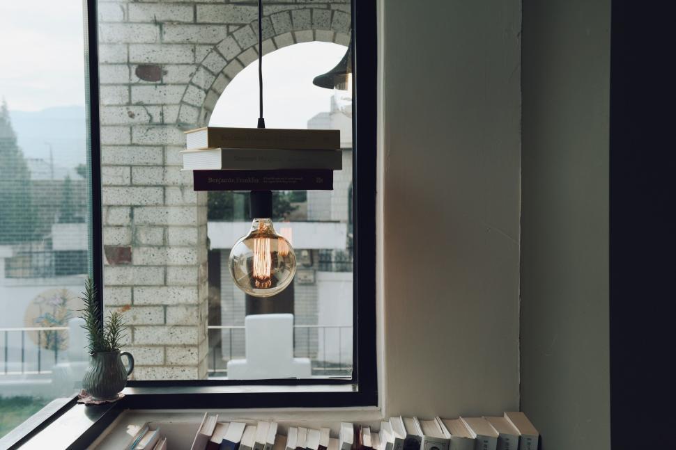 Free Image of Bookshelf and light bulb by a window with arch outside 