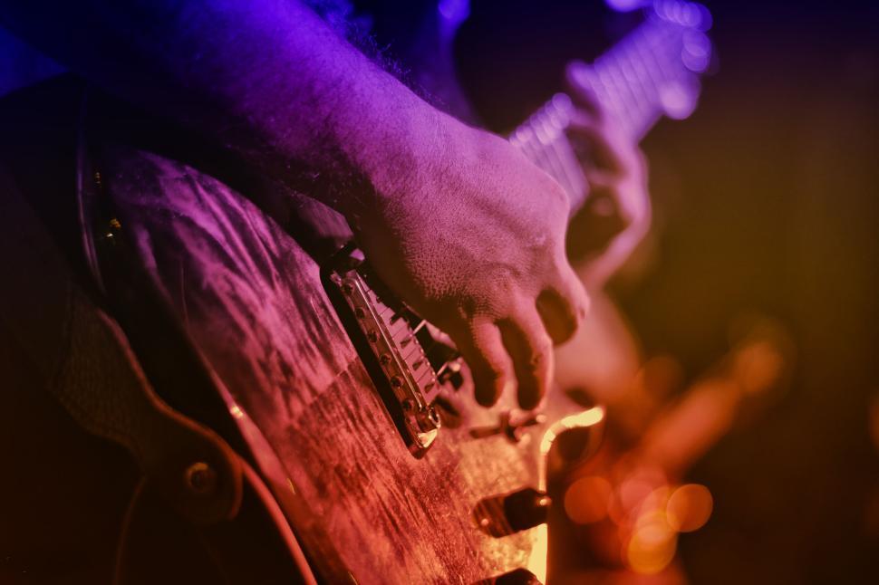 Free Image of Close-up of hand playing electric guitar with lighting 