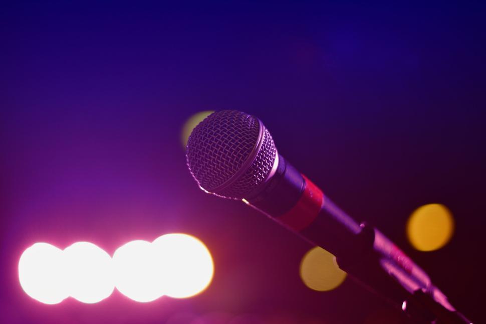 Free Image of Microphone on stage with colorful stage lights behind 