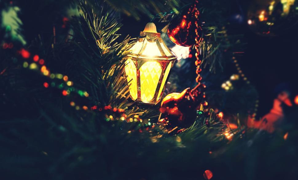 Free Image of Illuminated lantern on a Christmas tree with decorations. 