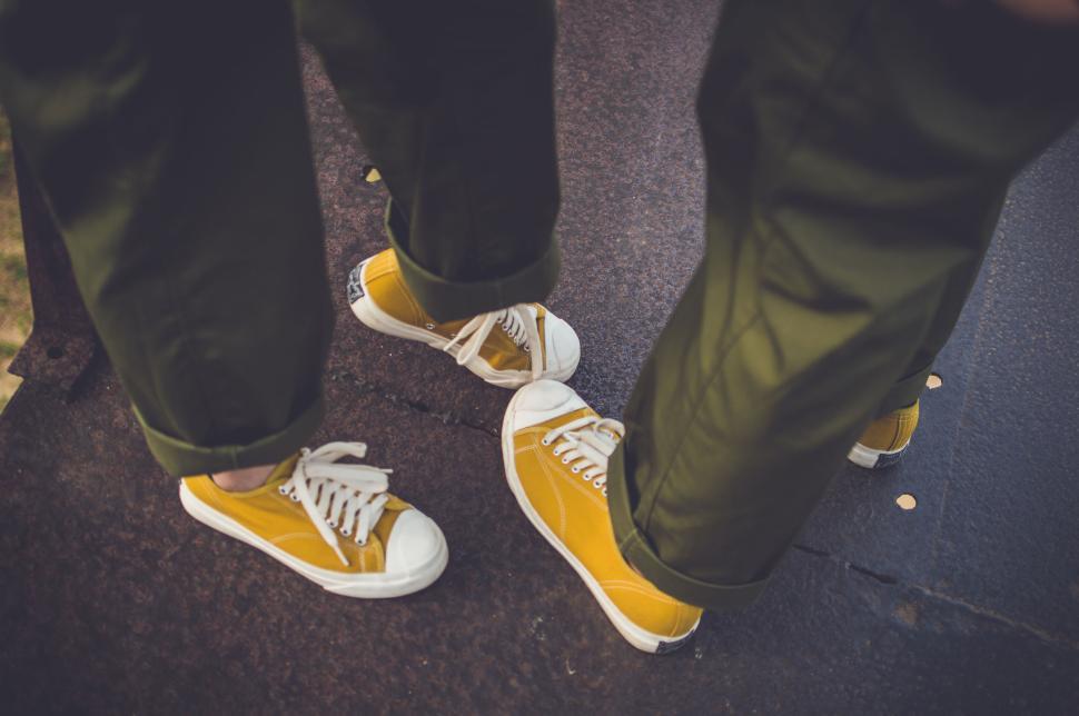 Free Image of Two people wearing yellow shoes on dark surface. 
