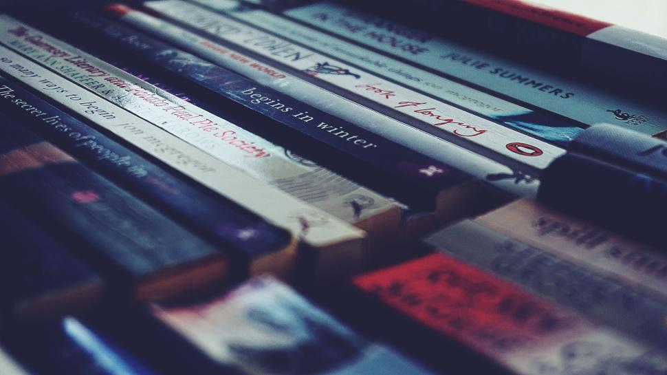 Free Image of Close-up of books on a shelf in varying titles and colors. 