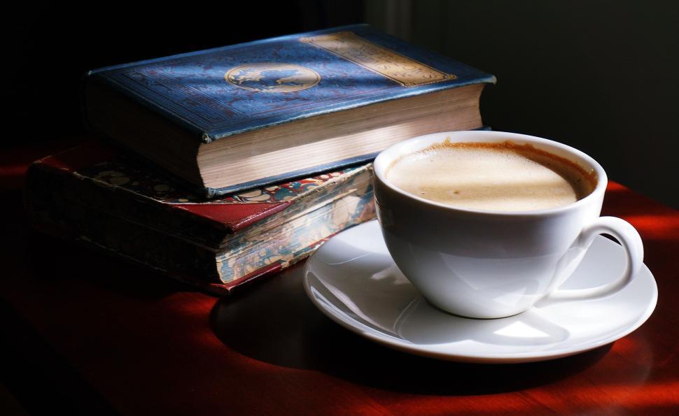 Free Image of Cup of coffee beside old books on a wooden table top. 