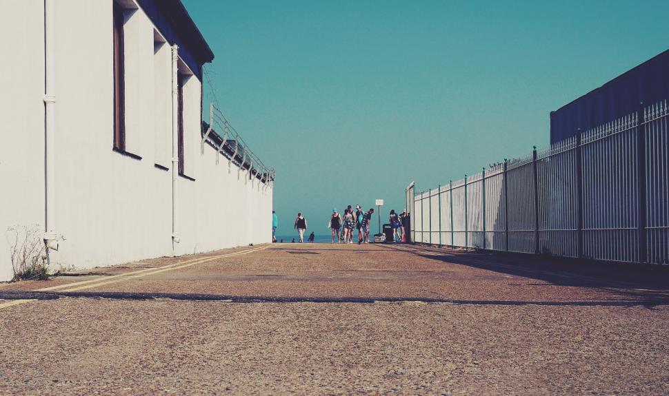 Free Image of Perspective view of a narrow alleyway leading to beach. 