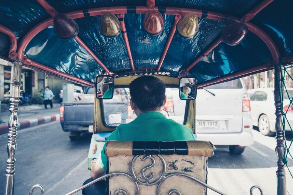Free Image of Man driving a tuk-tuk in busy city traffic. 