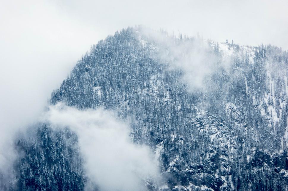 Free Image of Snow-covered mountain with misty clouds around peak 