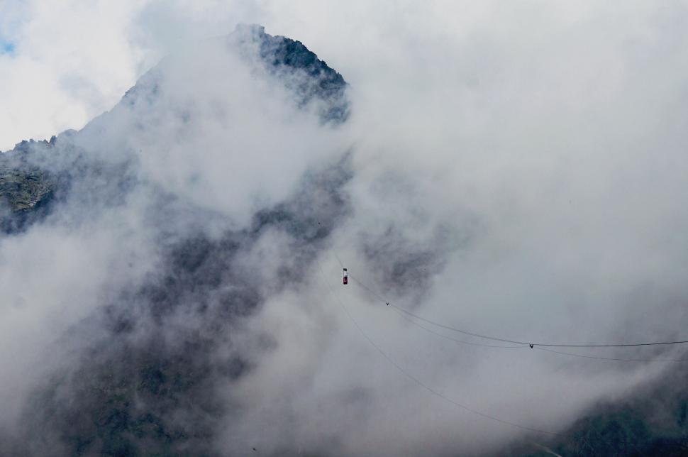 Free Image of Cable car ride up a foggy mountain peak in background. 