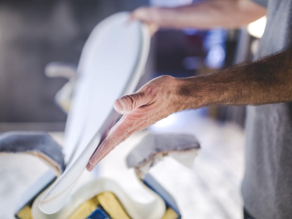 Free Image of Hands crafting and shaping a surfboard in workshop. 