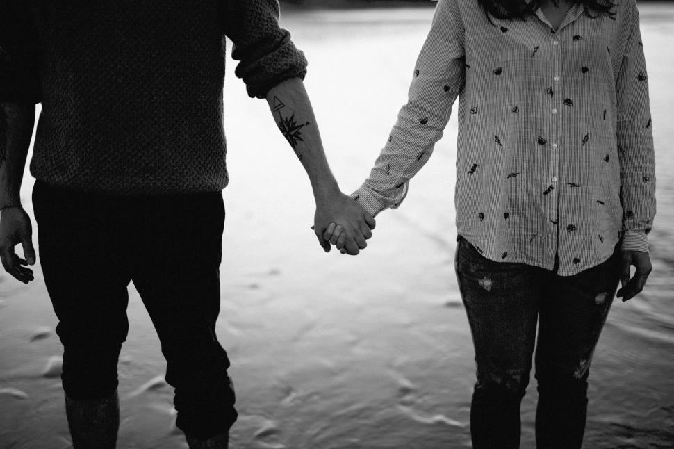 Free Image of Couple holding hands standing in shallow water. 