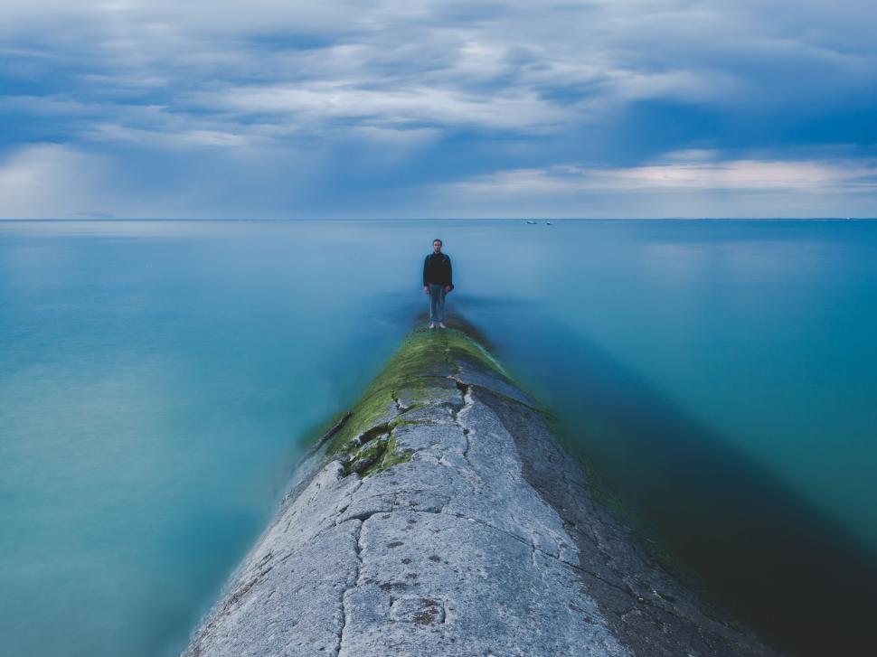 Free Image of Person standing on a pier extending into the ocean 
