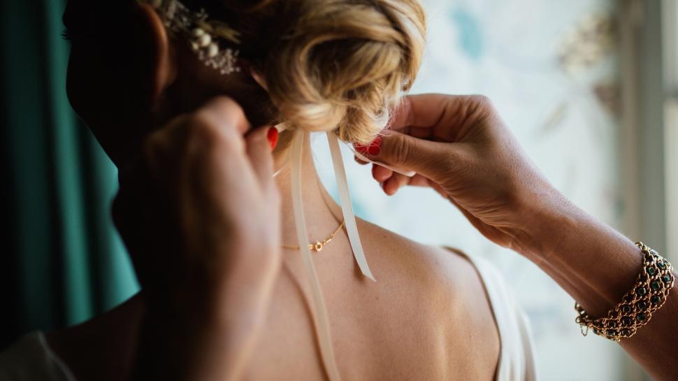 Free Image of Bride adjusting hair ribbon before wedding ceremony. 