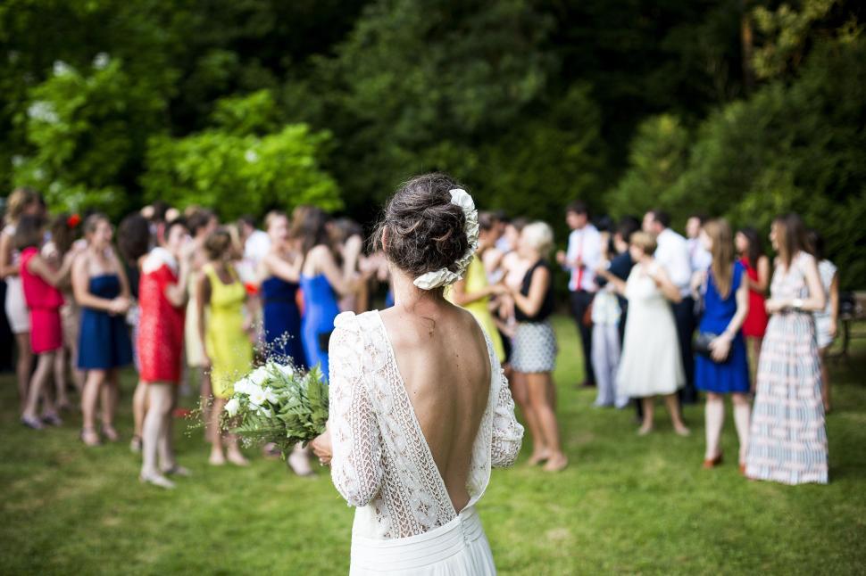 Free Image of Bride standing with bouquet, back view at outdoor event. 