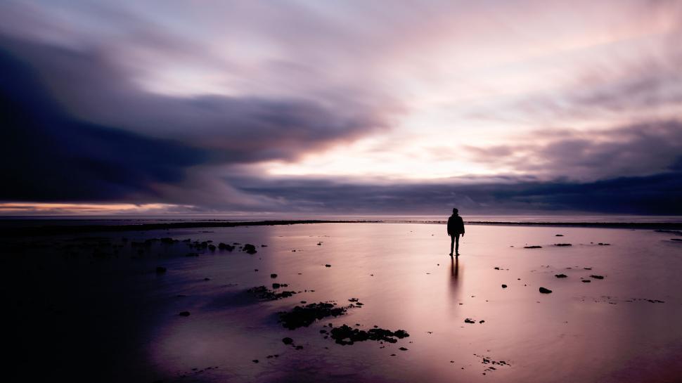 Free Image of Person standing alone on vast beach at twilight. 