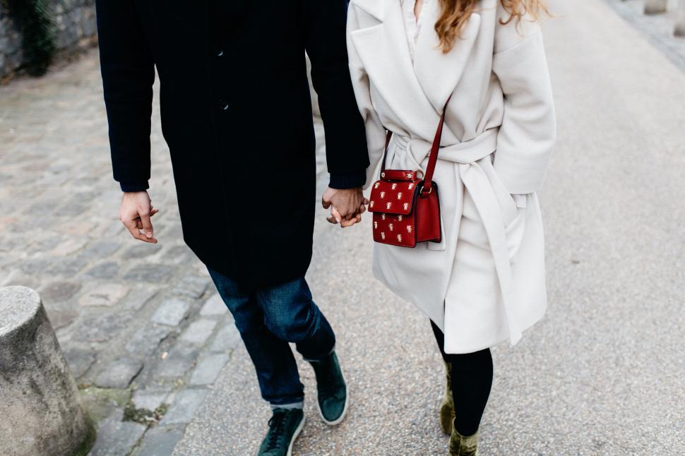 Free Image of Couple walking hand in hand dressed in coats 