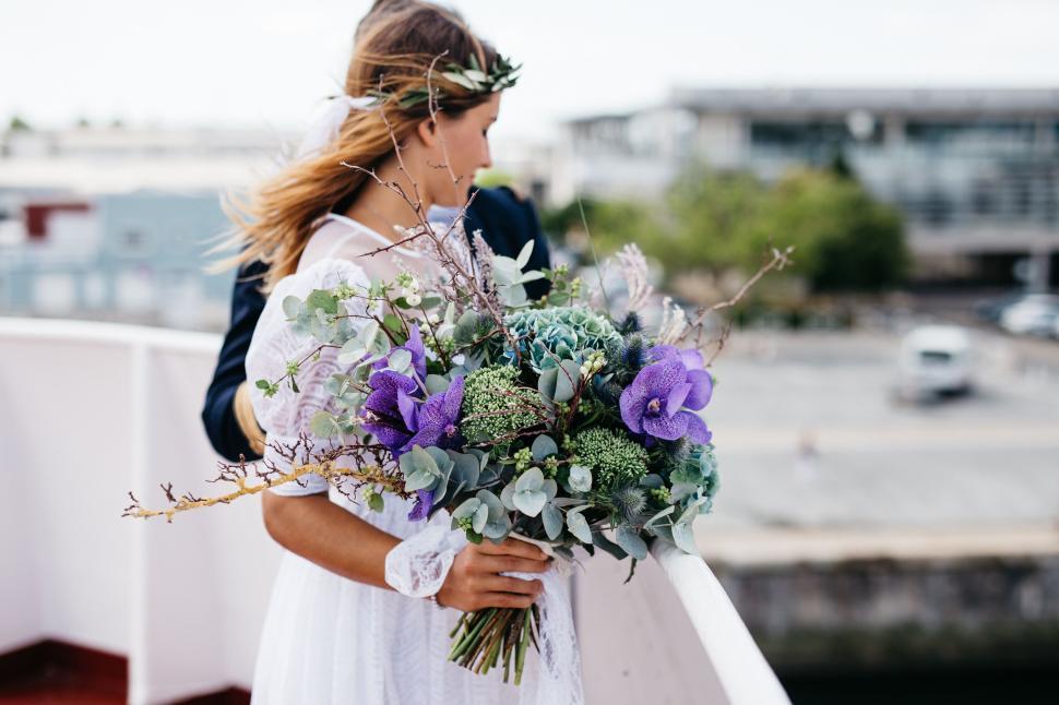 Free Image of Bride holds beautiful bouquet during wedding on a boat 