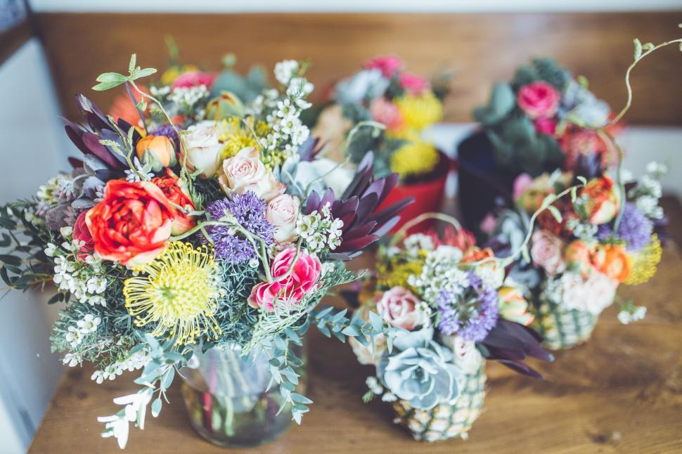 Free Image of Colorful bouquets in jars arranged on wooden table surface 