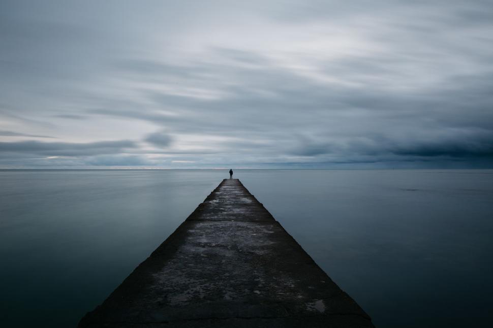 Free Image of Person standing on pier facing endless sea horizon. 