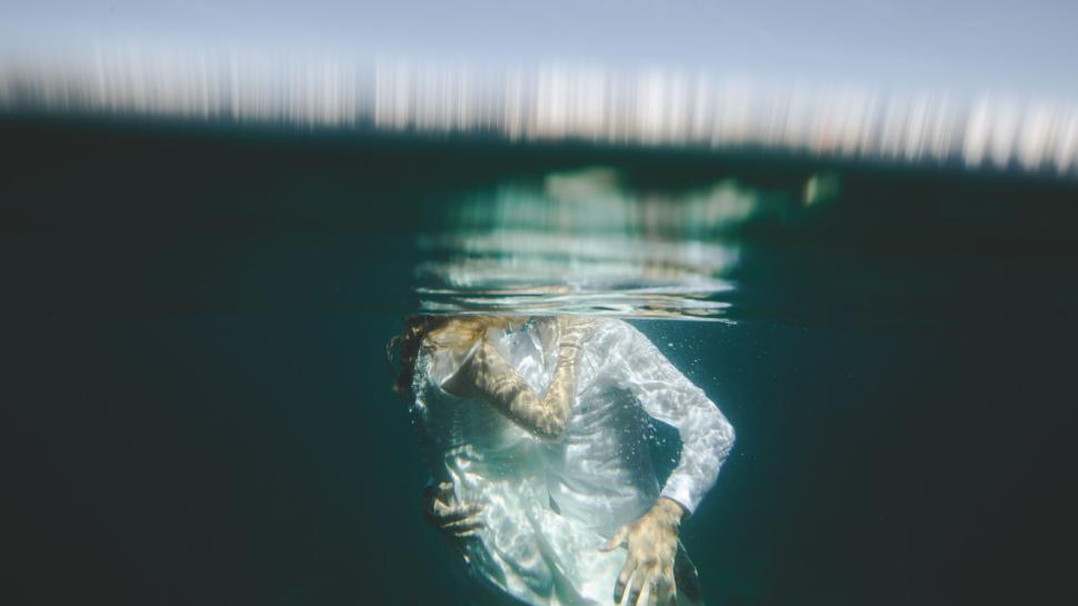 Free Image of Half-submerged person in water wearing white clothes 