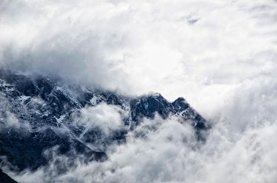 Free Image of Snow covered mountains partially hidden by thick clouds 