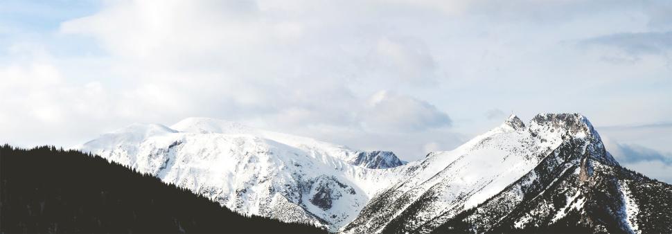 Free Image of Snow-covered mountain range under bright sky panorama 