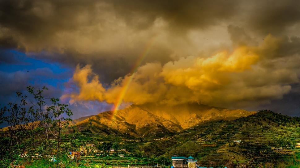 Free Image of Dramatic sunset with rainbow over scenic mountain range 