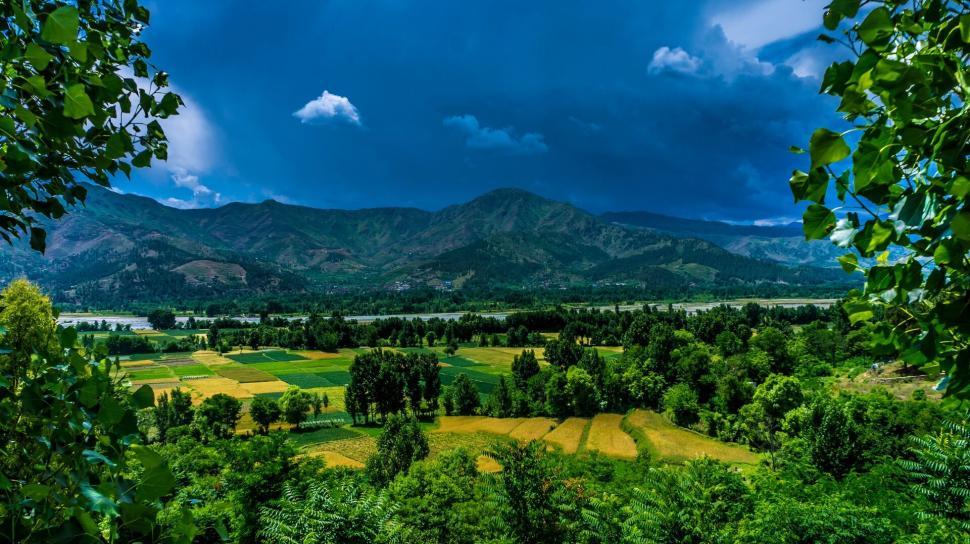Free Image of Lush green valley against majestic mountains and sky 