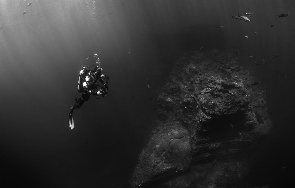 Free Image of A scuba diver explores underwater rock formations alone. 