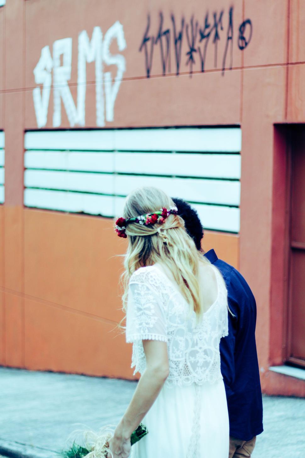 Free Image of Bride with floral crown walking with partner outdoors. 