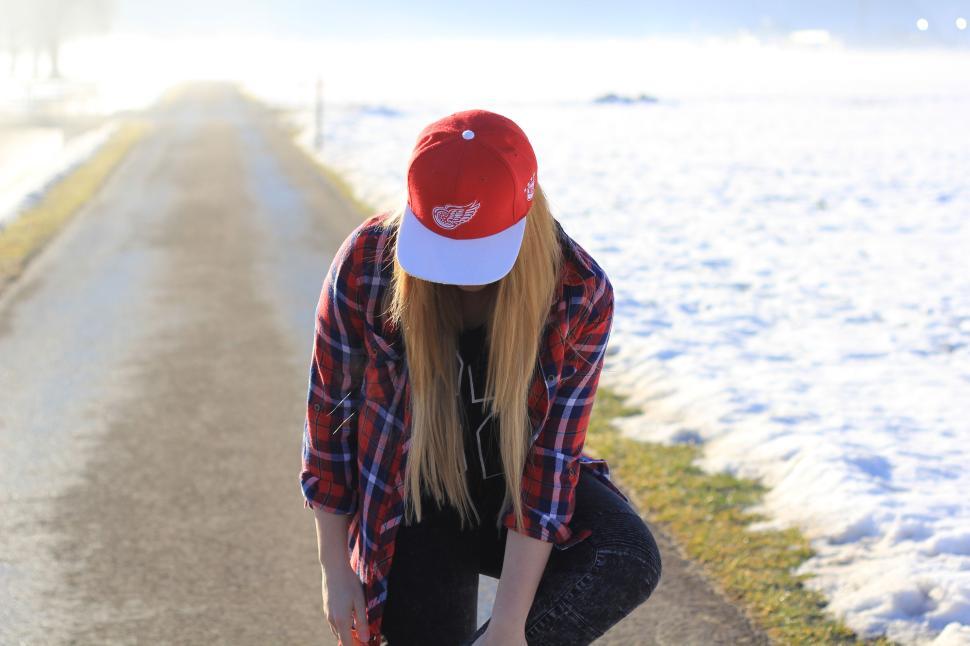 Free Image of Young woman in winter setting wearing red cap and plaid. 