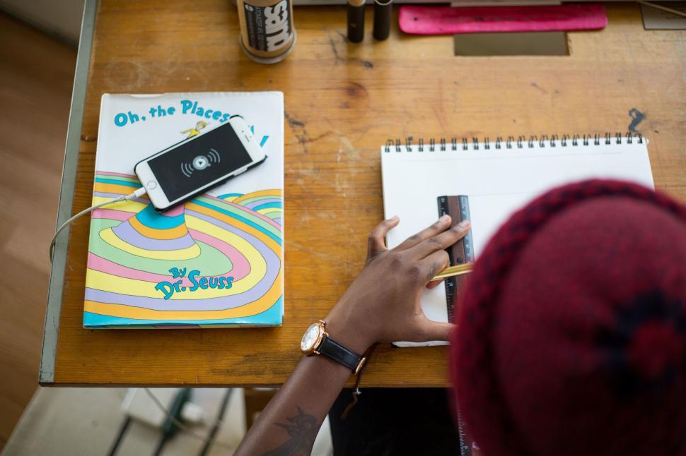 Free Image of Person with book and phone drawing straight lines 