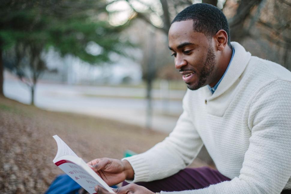 Free Image of Man reading a book outside in a peaceful park 
