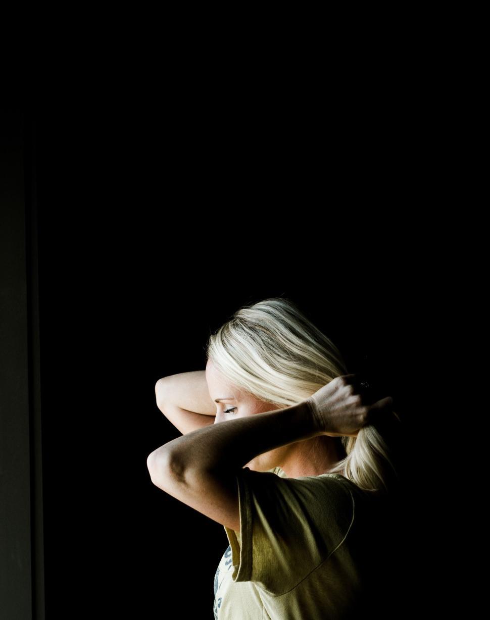 Free Image of Person fixing hair against dark dramatic background 