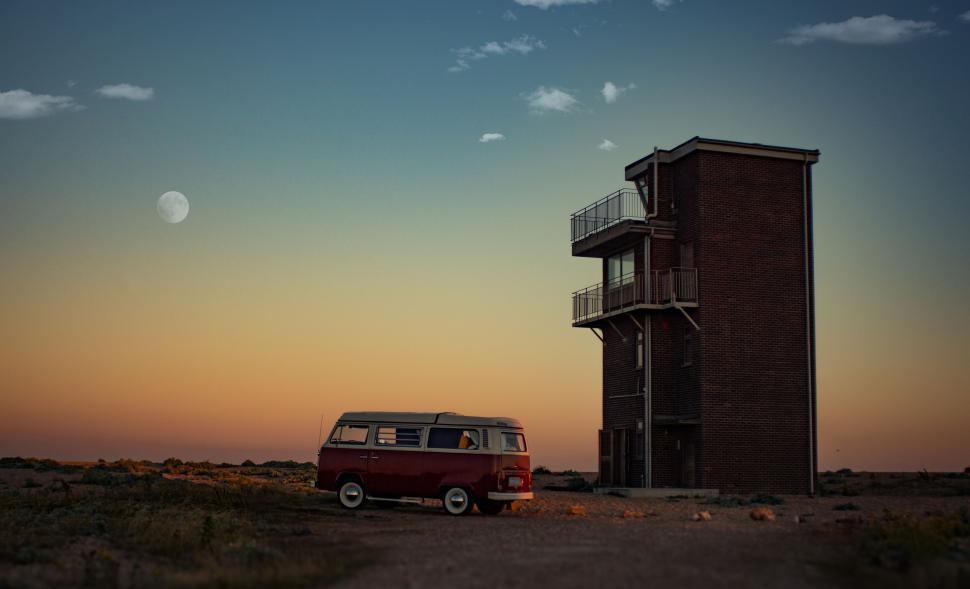 Free Image of Vintage van parked near a tall narrow building at dusk. 