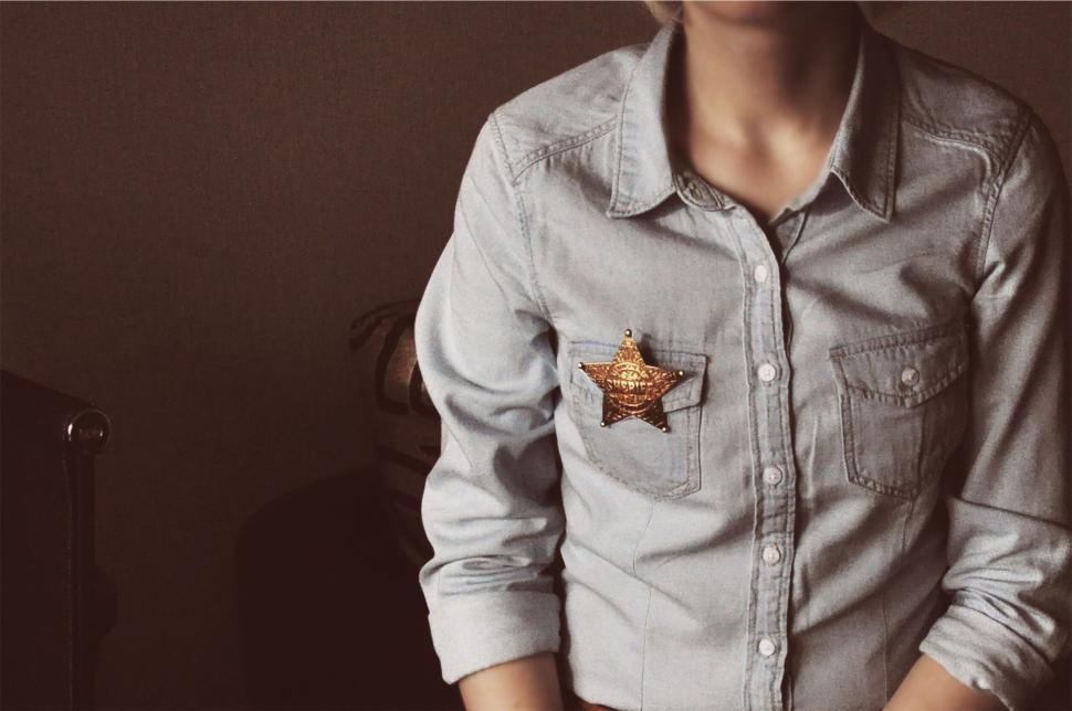 Free Image of Person with a sheriff badge on denim shirt background 