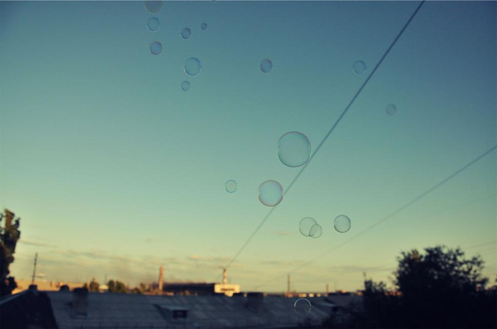 Free Image of Soap bubbles floating over rooftops during sunset sky 