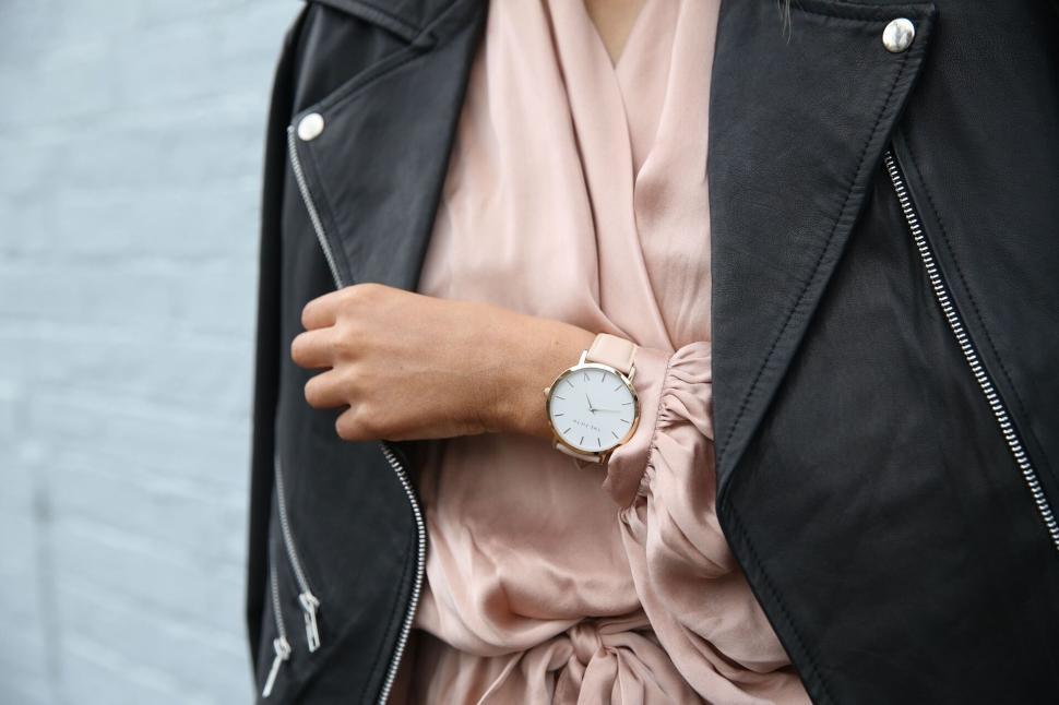 Free Image of Person wearing leather jacket and wristwatch on grey wall 